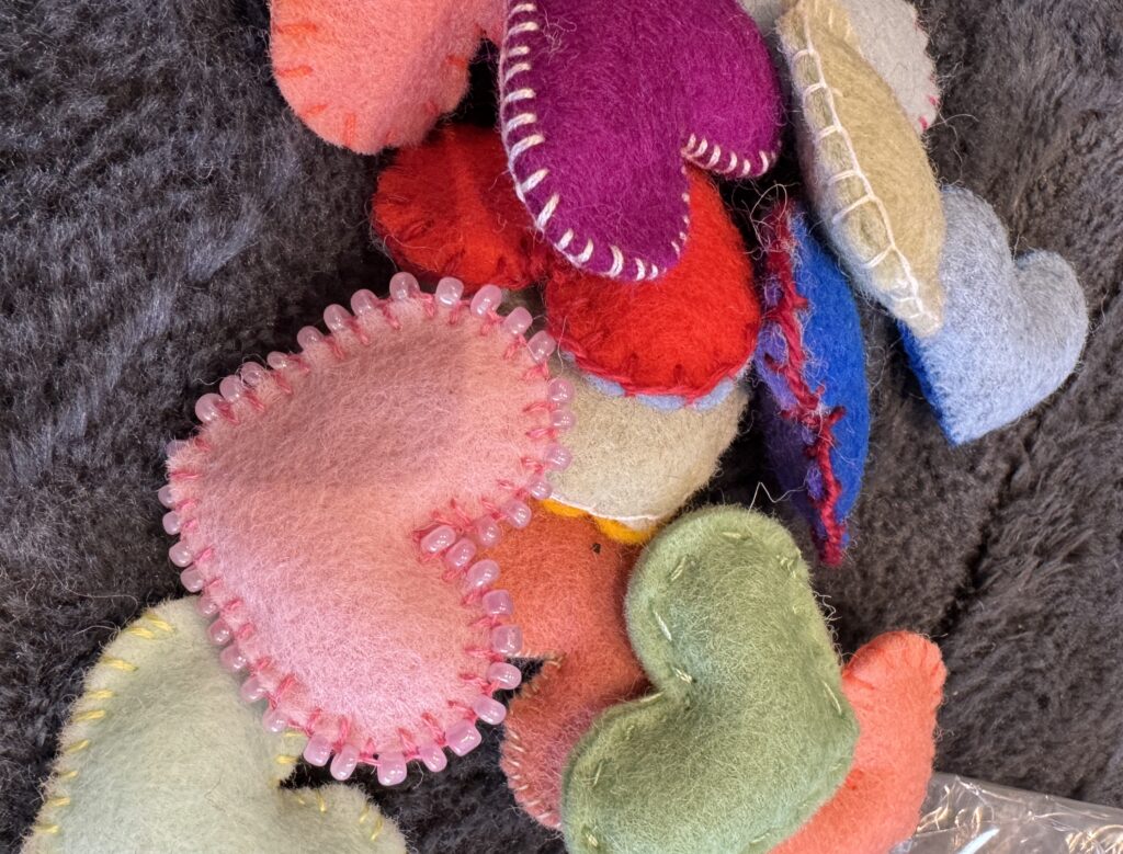 A selection of handmade felt hearts on a grey rug
